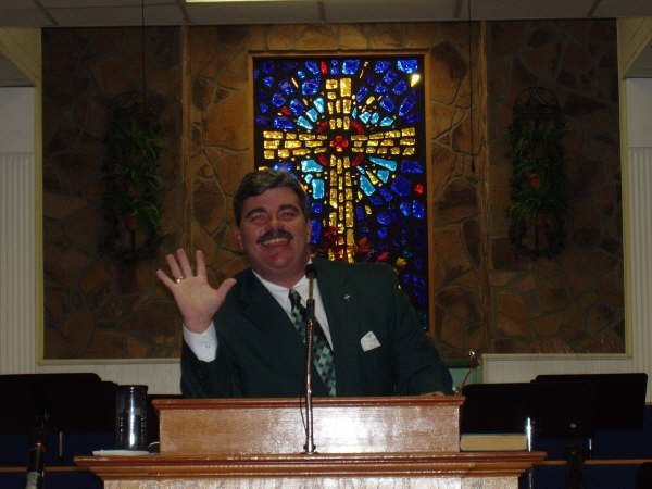 Pastor Buddy Burnett waving hello from the pulpit at Connections Community Church